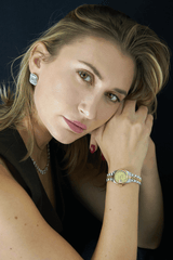 Woman wearing two-tone rolex and large stud diamond earrings.
