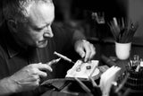 Man working on a small object with tools in a workshop setting