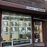 Time piece watch and jewelry repair storefront with display cases and 'Open' sign